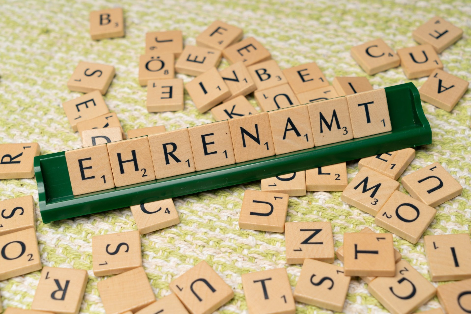 Hier sehen sie das Wort "Ehrenamt" das aus Scrabble Buchstaben zusammengelegt wurde.