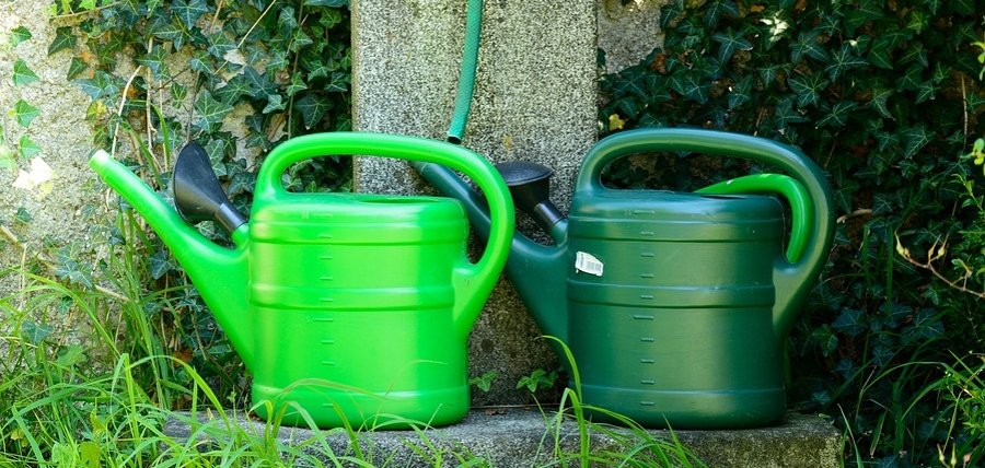Hier sehen Sie zwei Gießkannen vor einer Wasserstelle.
