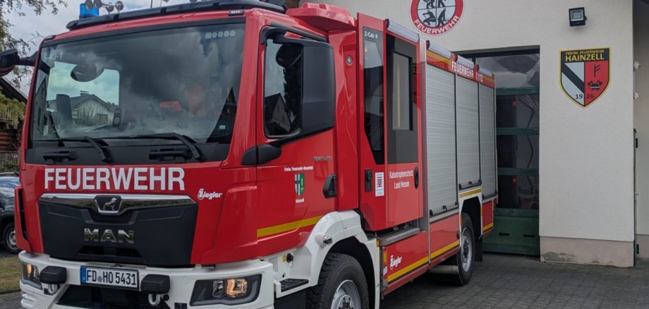 Hier sehen Sie das Feuerwehrhaus in Hainzell mit Feuerwehrauto davor.